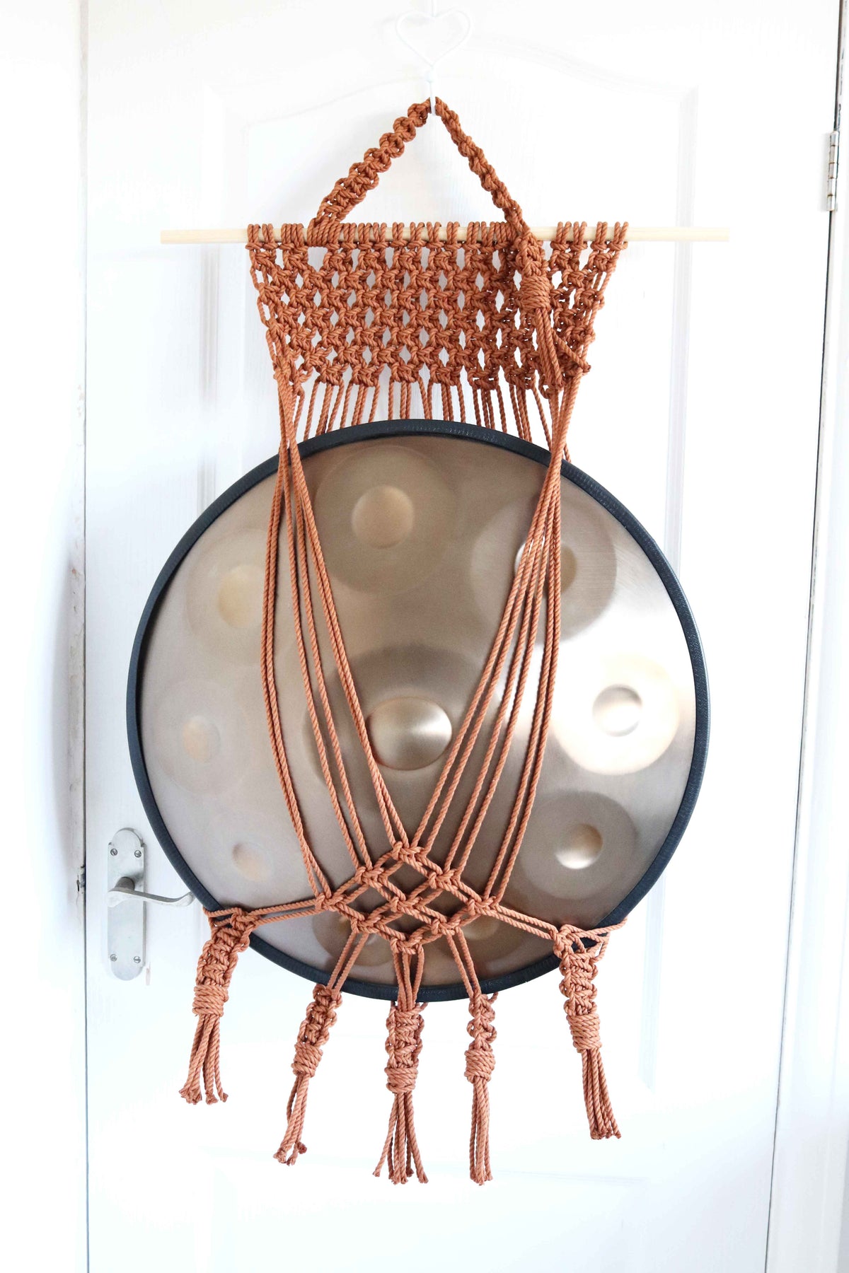 Copper macrame handpan hanger mount with extra netting on a pine dowel