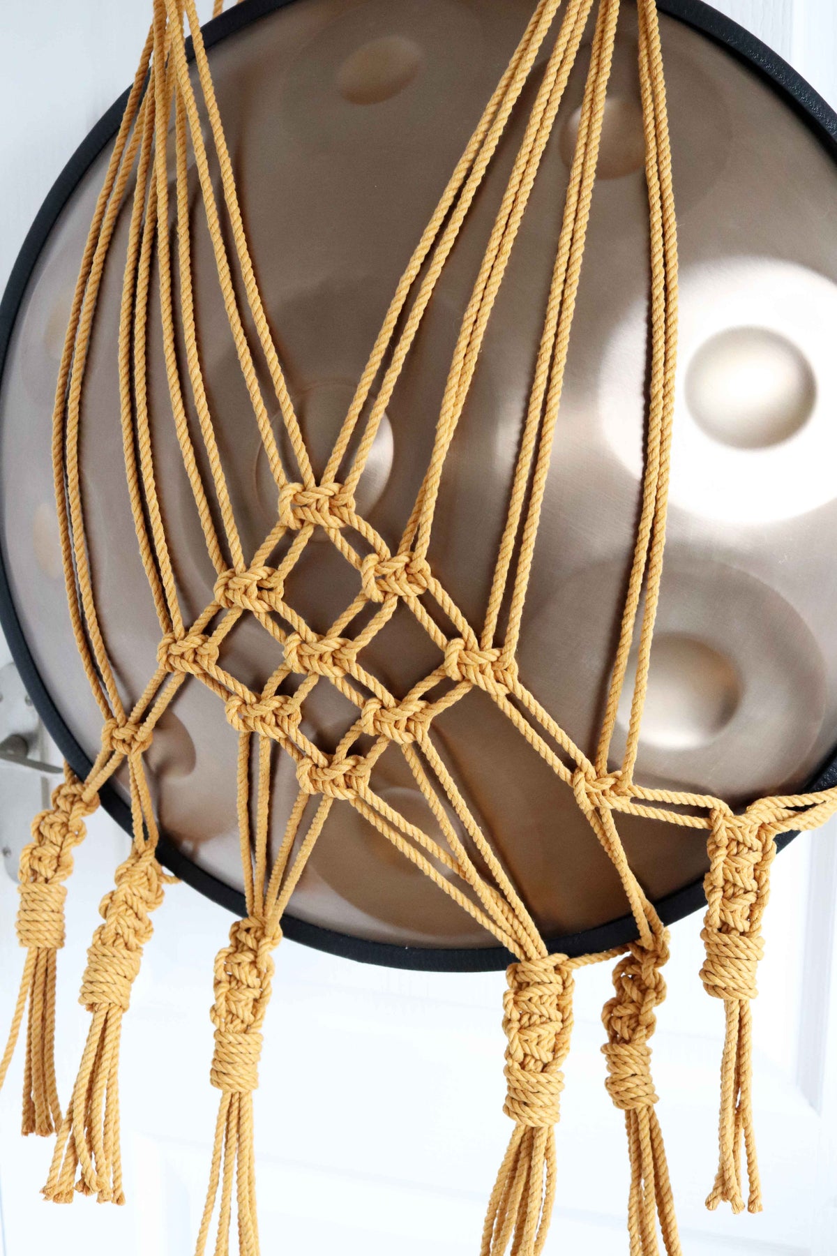 Mustard macrame handpan hanger with extra netting on a pine dowel