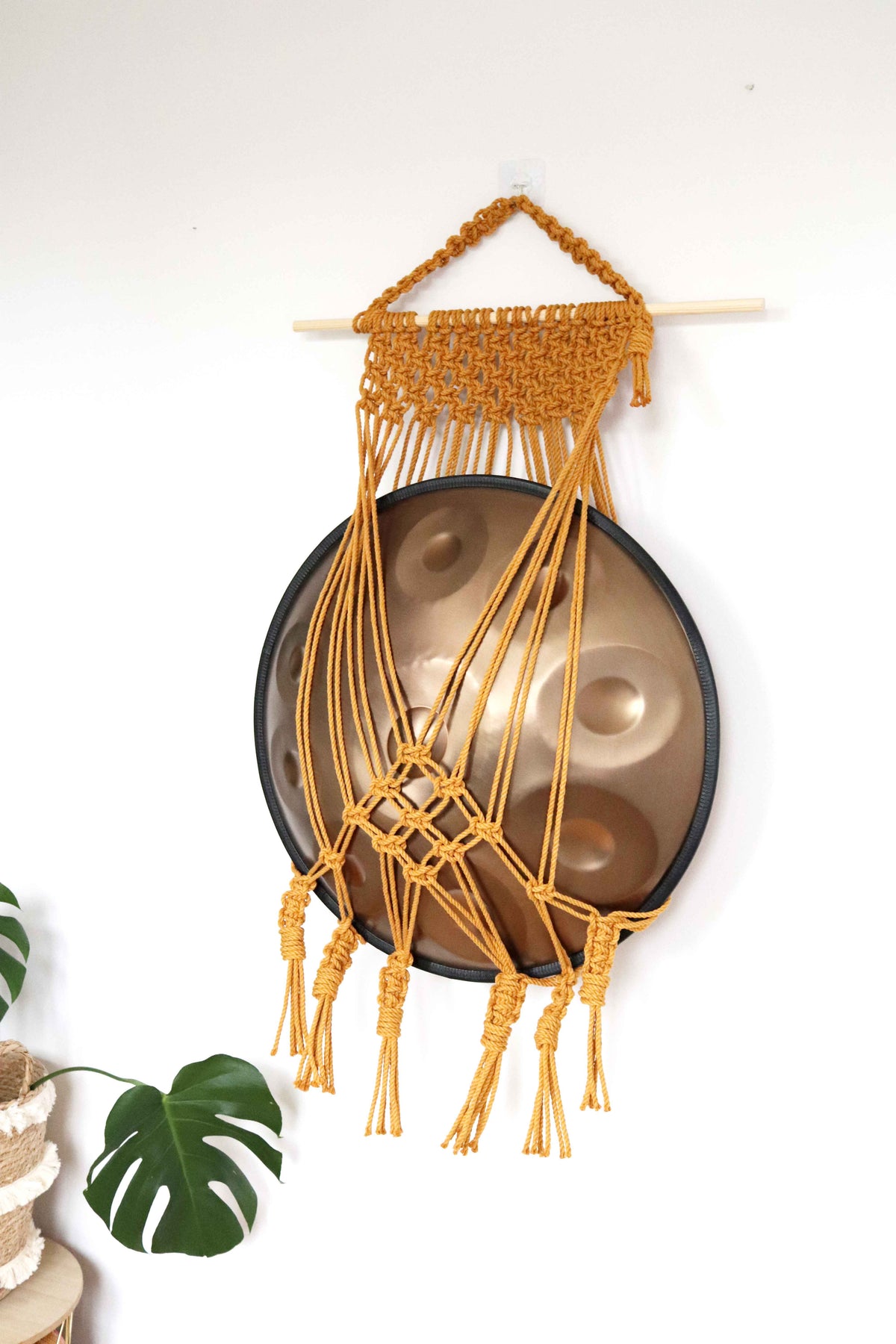 Mustard macrame handpan hanger with extra netting on a pine dowel