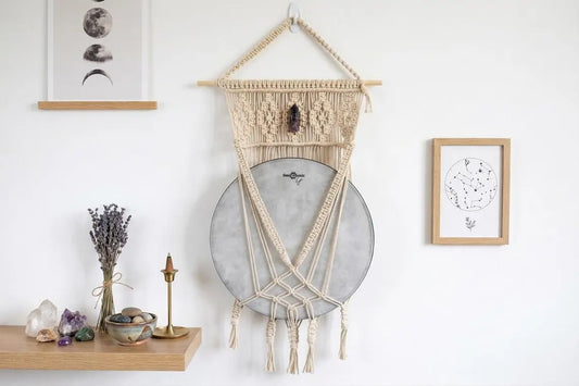 Macrame wall mount holding a hand drum with an amethyst crystal at the top