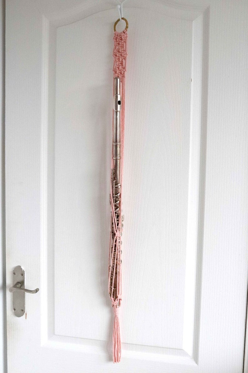 Pink macrame plant hanger hanging on a white door