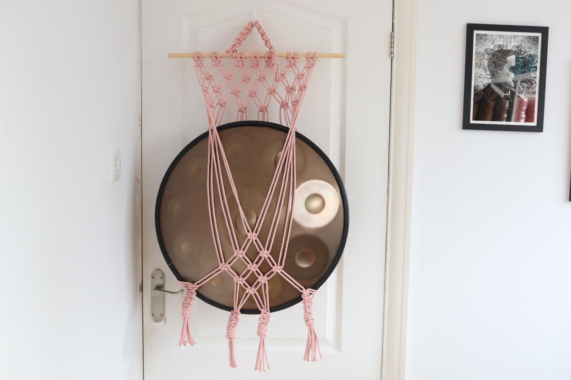 Macrame wall hanging on a door with a framed picture in the background