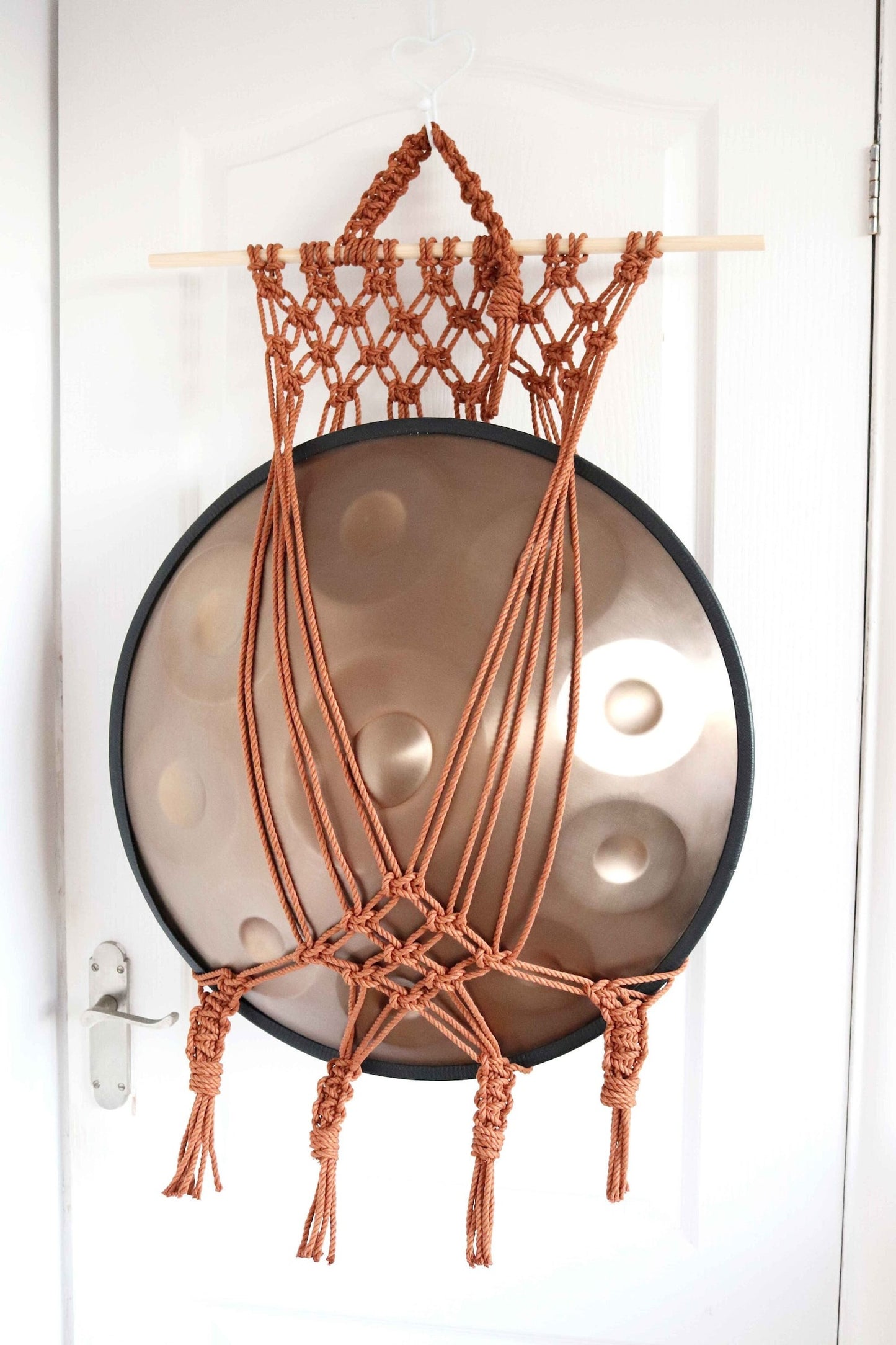 Handmade macrame handpan hanger with a netted design, displaying a handpan Tuning Fork.