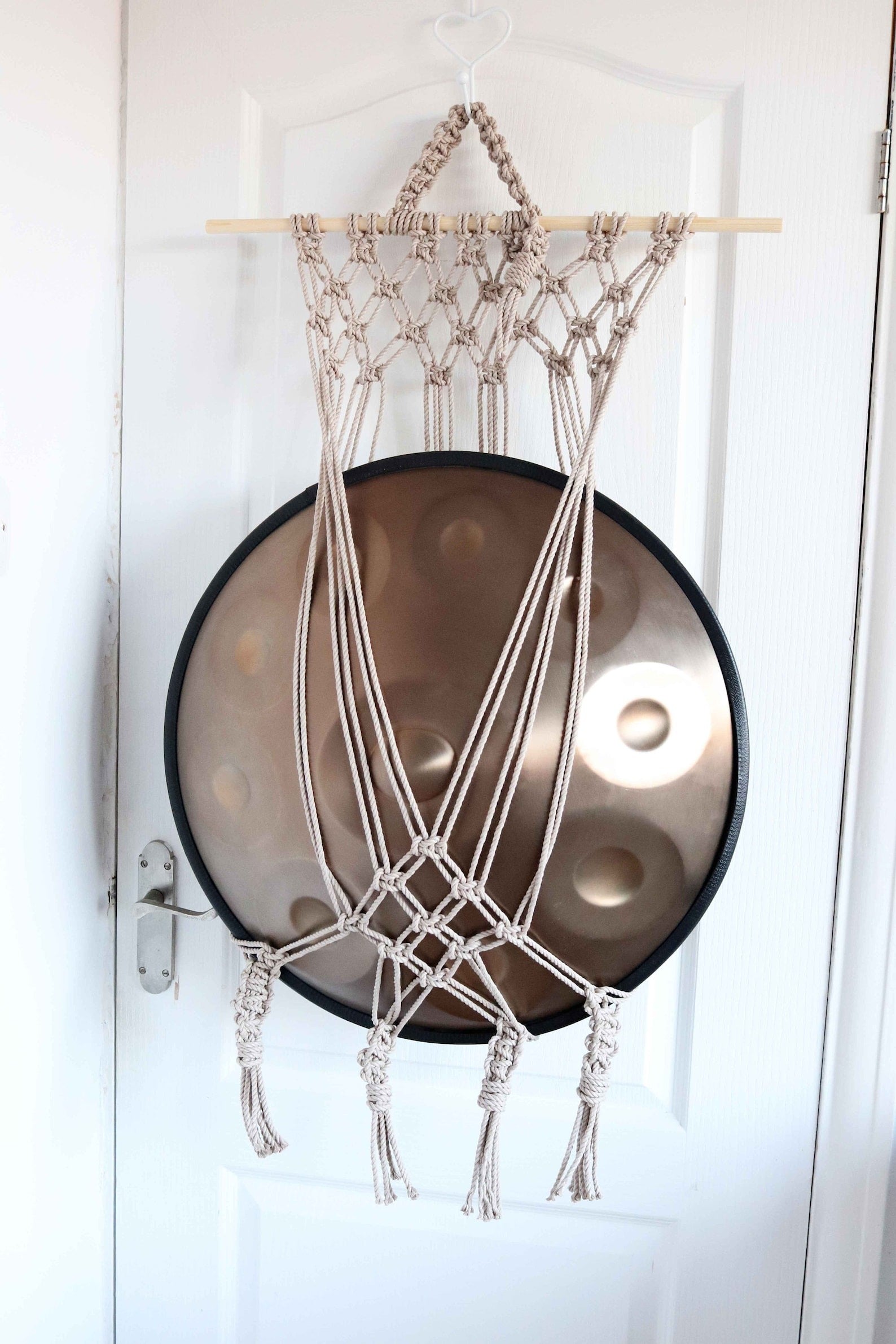 Handmade macrame handpan hanger with a netted design, displaying a handpan Tuning Fork.