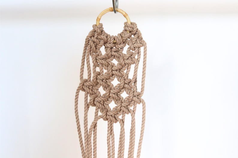 Macrame wall hanging with star patterns on a white background